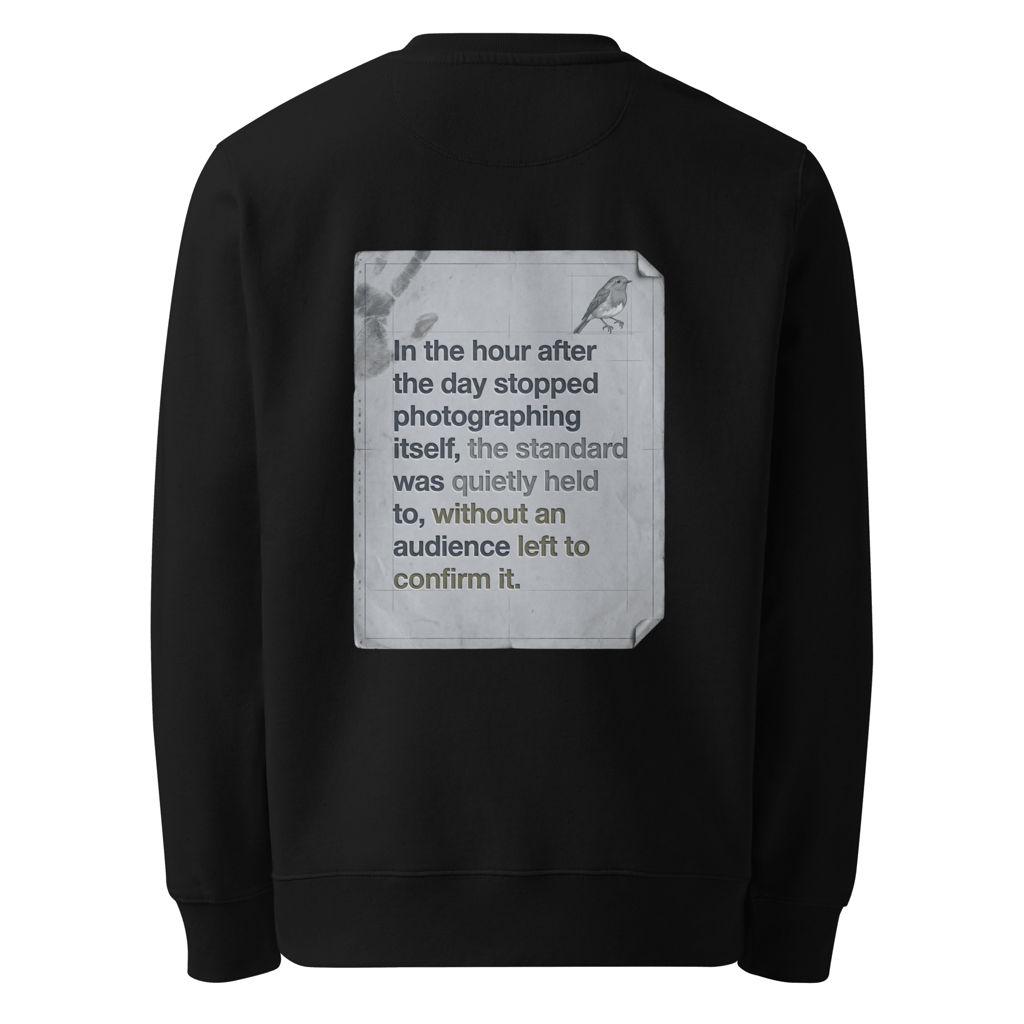 Quietly Held sweater, black — back view of torn paper slogan plate with robin, reading "In the hour after the day stopped photographing itself, the standard was quietly held to, without an audience left to confirm it." — Ricki Robin