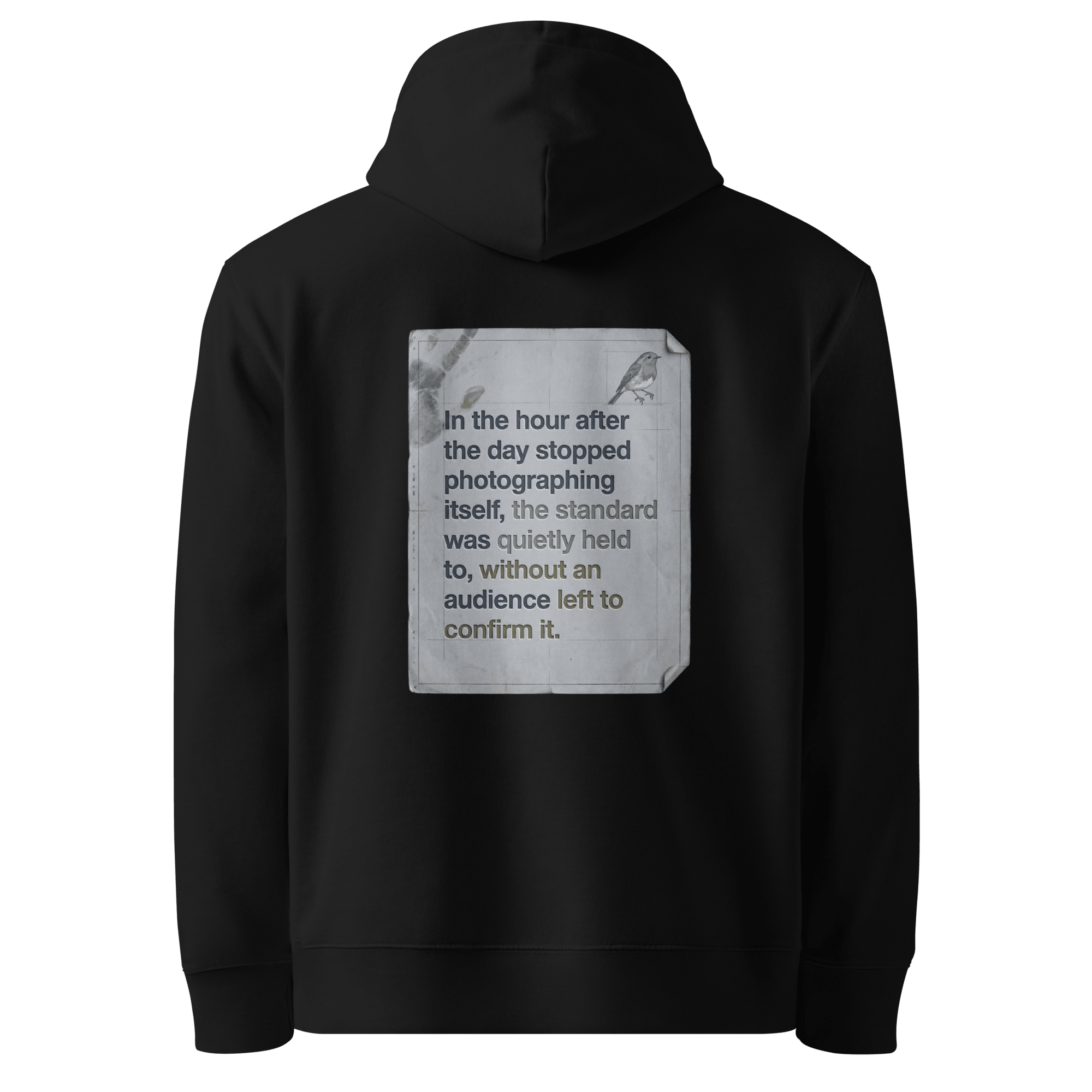 Quietly Held hoodie, black — back view of torn paper slogan plate with robin, reading "In the hour after the day stopped photographing itself, the standard was quietly held to, without an audience left to confirm it." — Ricki Robin