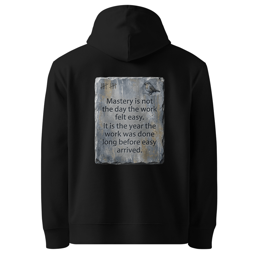 Long Before Easy hoodie, black — back view of worn metal slogan plate with robin, reading "Mastery is not the day the work felt easy. It is the year the work was done long before easy arrived." — Ricki Robin